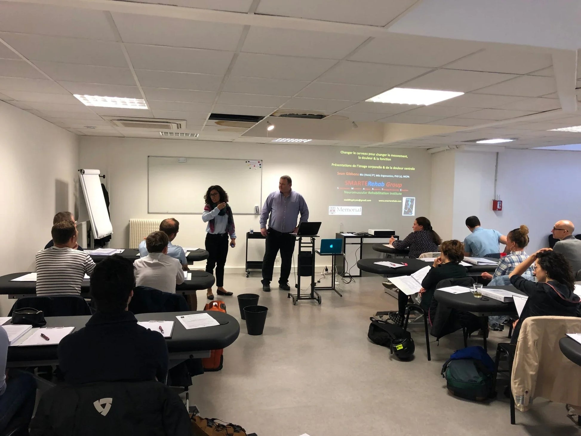 Formation en kinésithérapie Kpten, salle de classe avec participants et présentation sur écran.